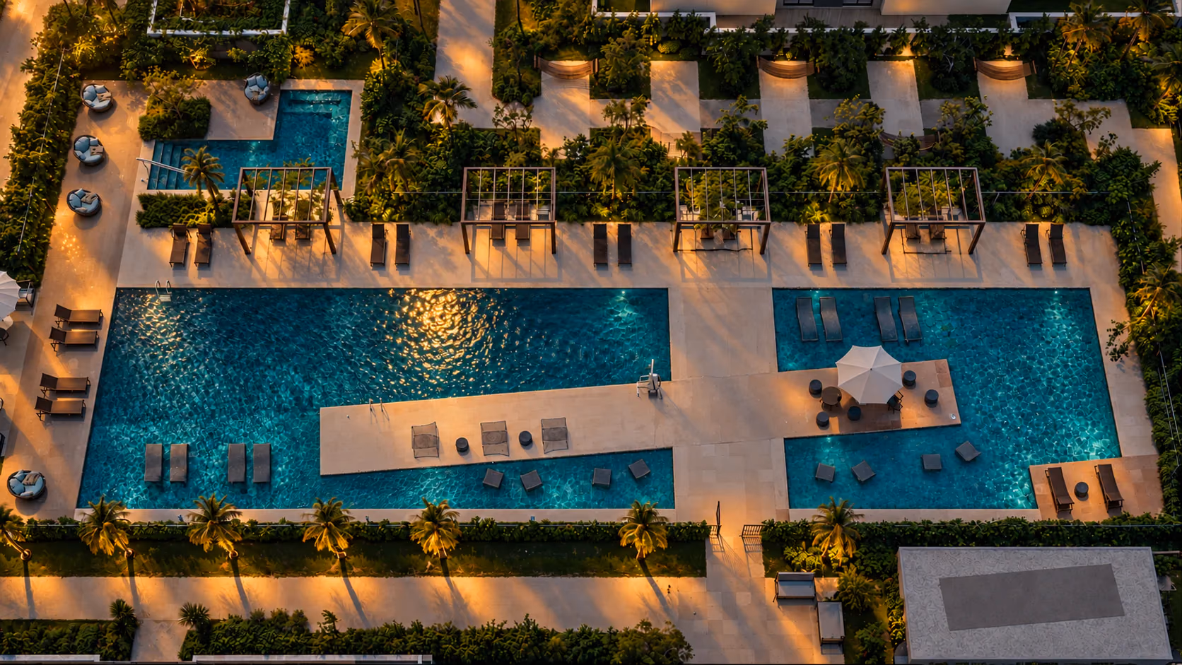 Vista aérea das piscinas do Aura Tamboré ao entardecer, com deck, pérgolas e jardins